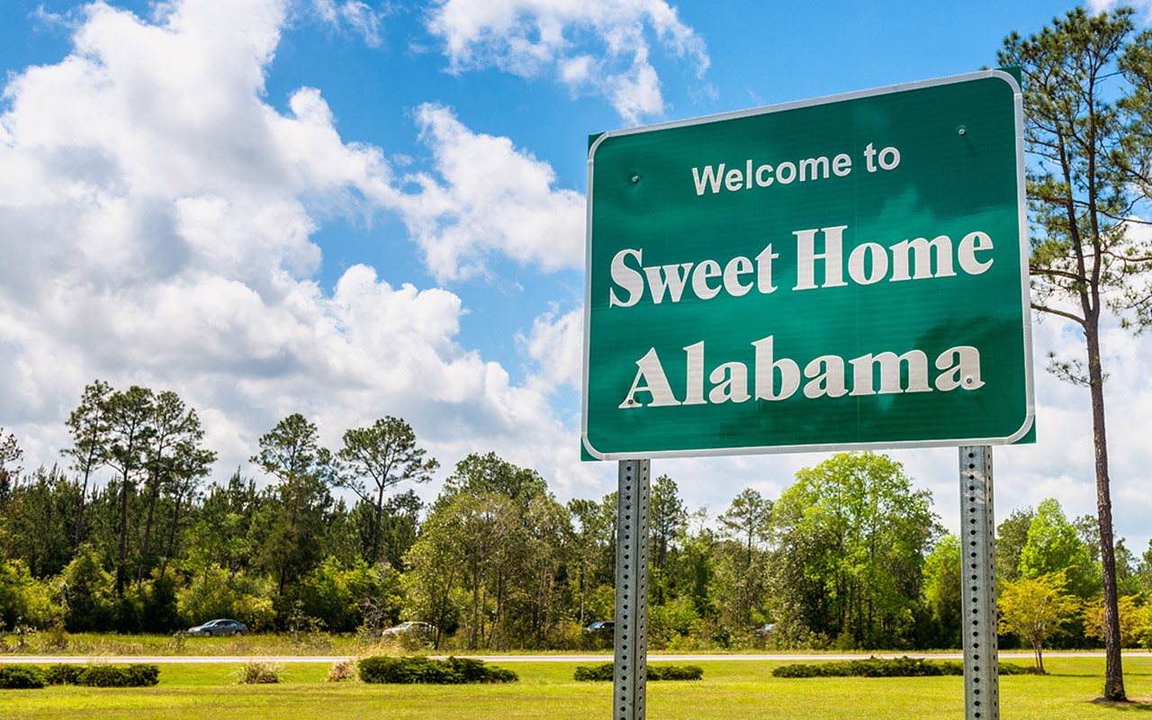 Image of a road sign on the Alabama state line reading 'Welcome to Sweet Home Alabama'