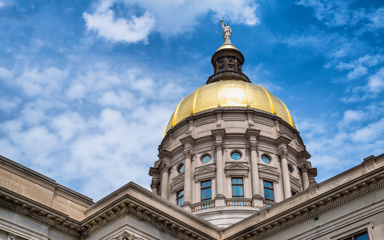 The Georgia statehouse building is shown against a blue, slightly cloudy sky