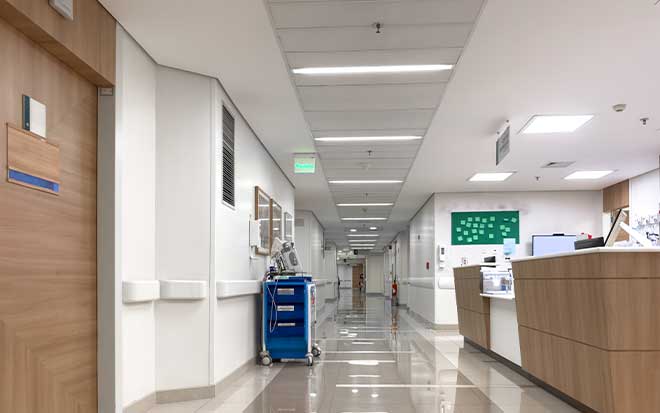 Photo of a long hospital hallway with reception desks and closed doors
