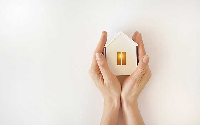 Image of hands holding a small model house