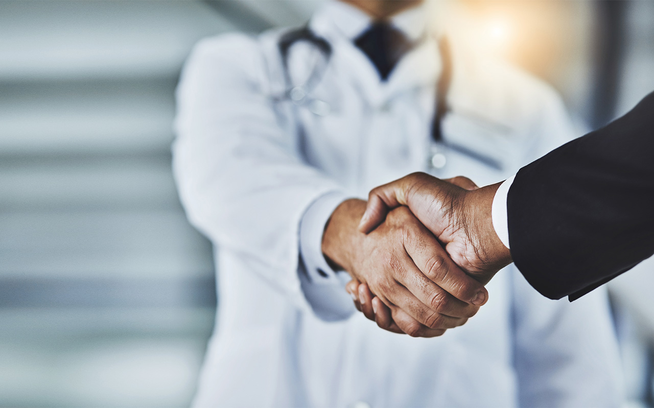 Cropped shot of a doctor shaking hands with a businessman in a hospital