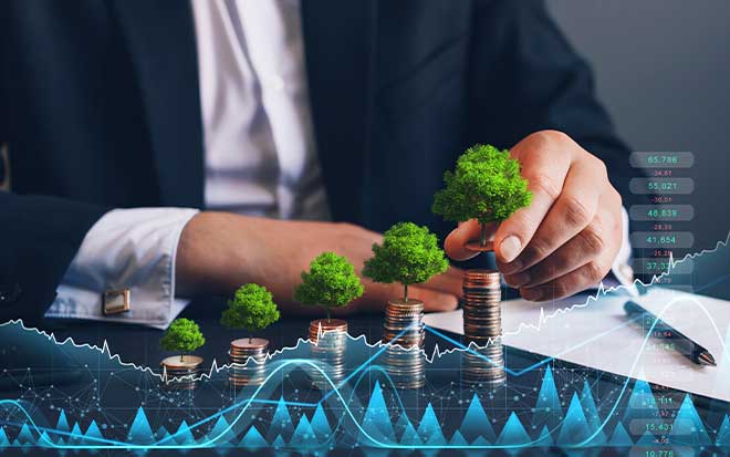 Businessman placing a small tree on a stack of coins with financial charts overlaid, symbolizing sustainable finance, ESG investing, and long-term financial growth.