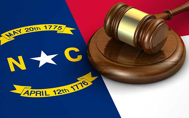 A gavel and North Carolina stat flag rest on a table.
