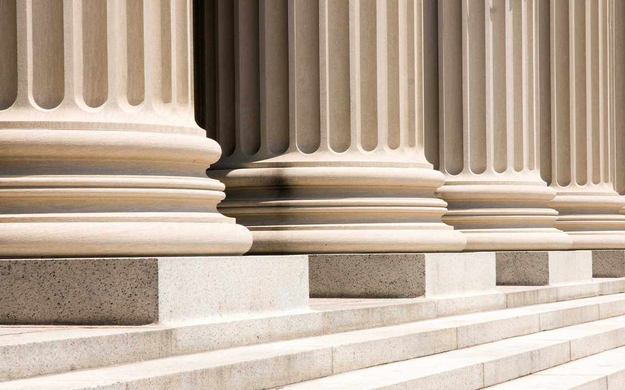 Row of classical-style stone columns leading up to the steps of a courthouse