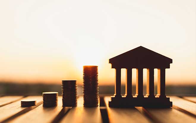 Image of mini bank next to stacked coins