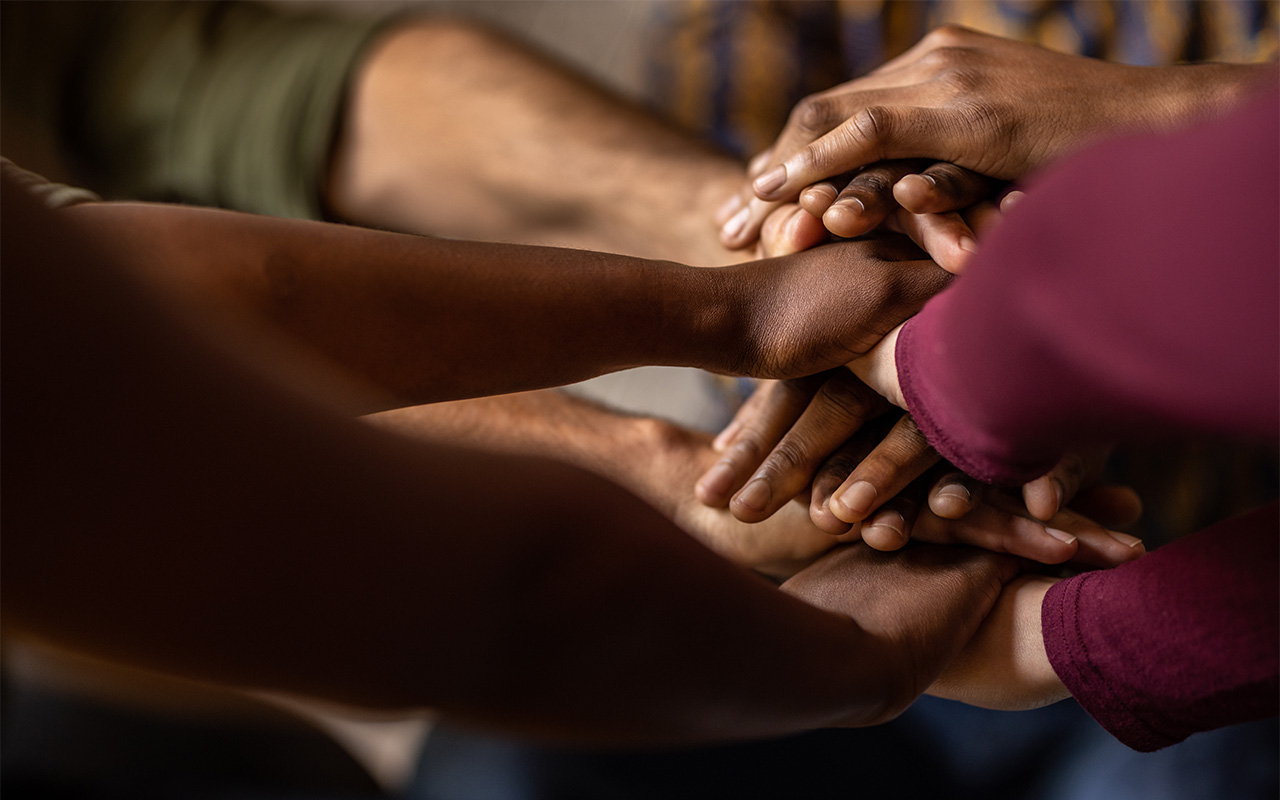 Closeup of a diverse team of businesspeople sitting in a huddle with their hands together in an office