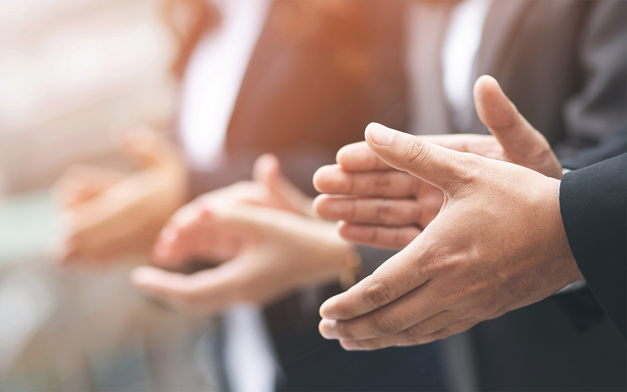 Business men and women clapping their hands.