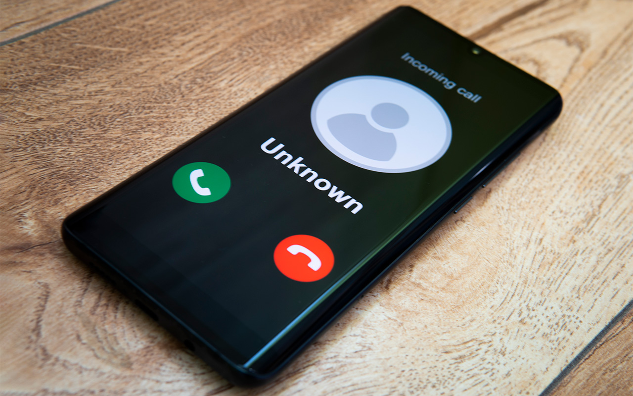 Phone call from unknown number. Scam, fraud or phishing with smartphone concept. Prank caller, scammer or stranger. call from an unknown caller, a smartphone on a wooden table.