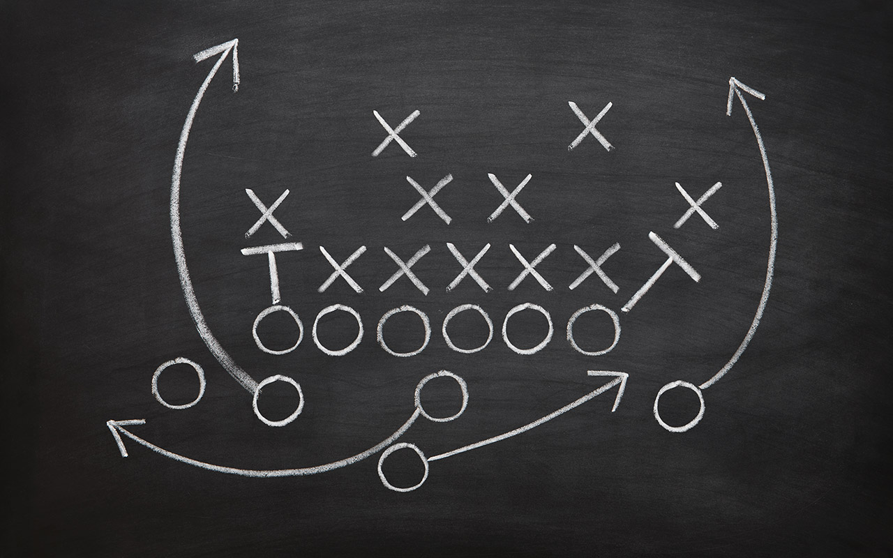 A football play is drawn out on a chalkboard.