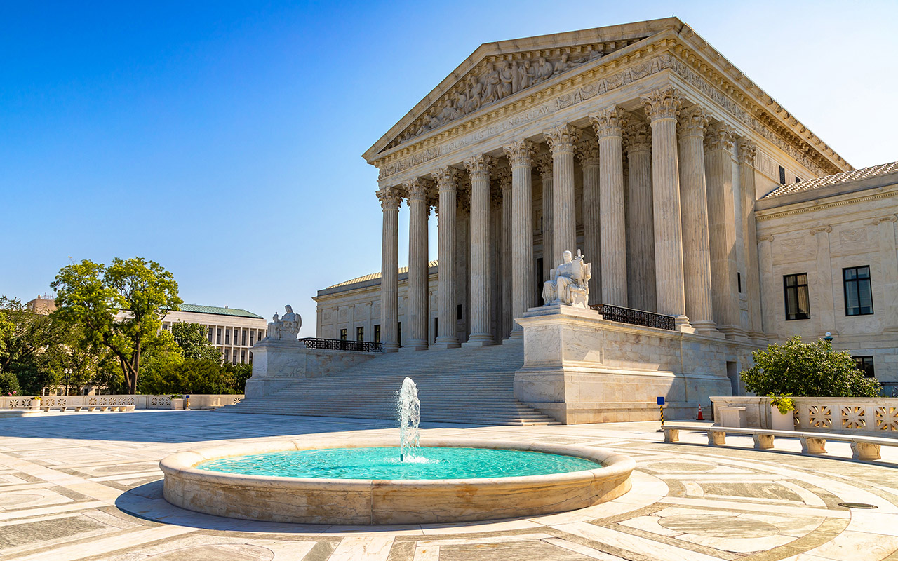 Photo of U.S. Supreme Court building on a sunny day with water feature in front.