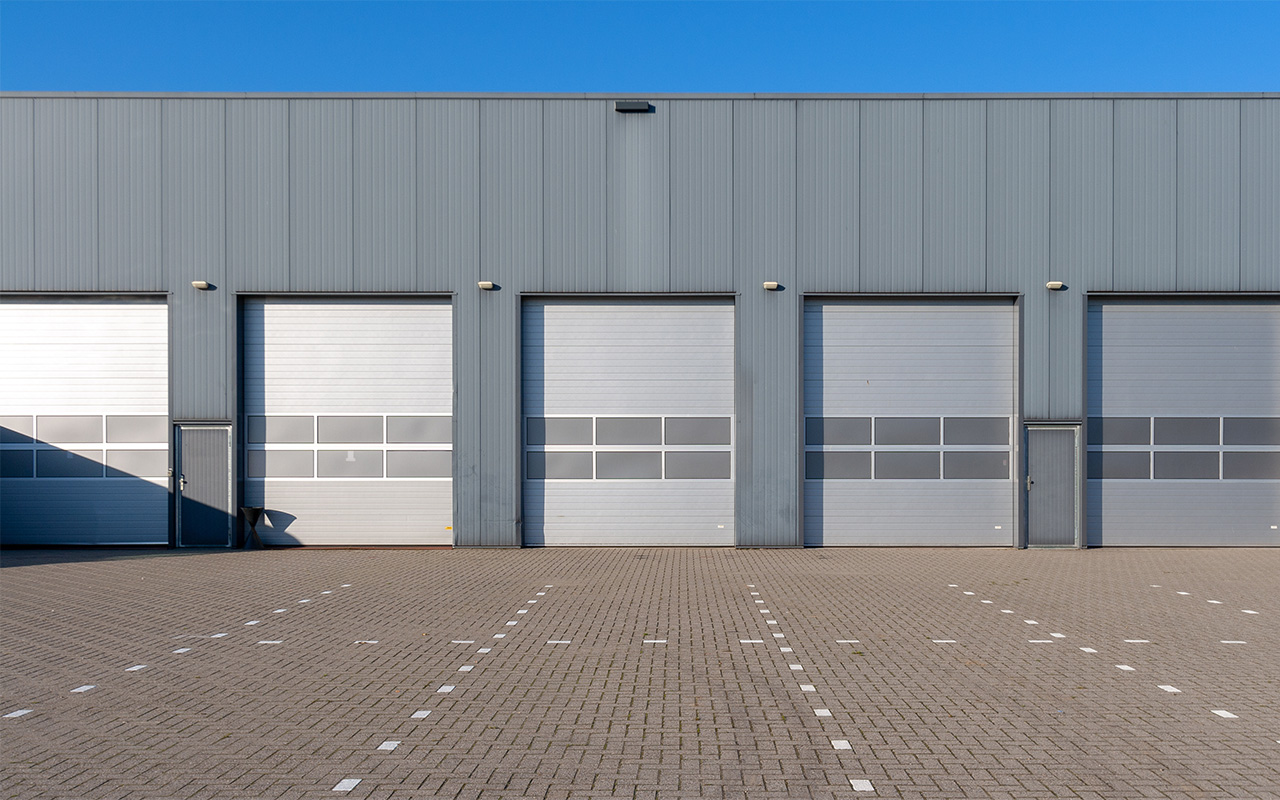 Row of grey industrial Units with roller shutter doors.