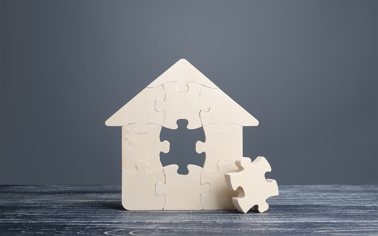 A puzzle in the shape of a house, with the missing middle piece off to the side.