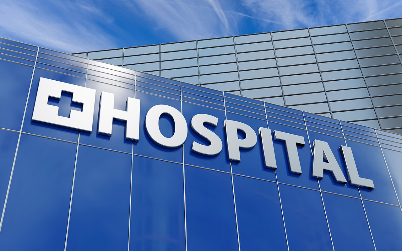 A hospital symbol on a glass building.