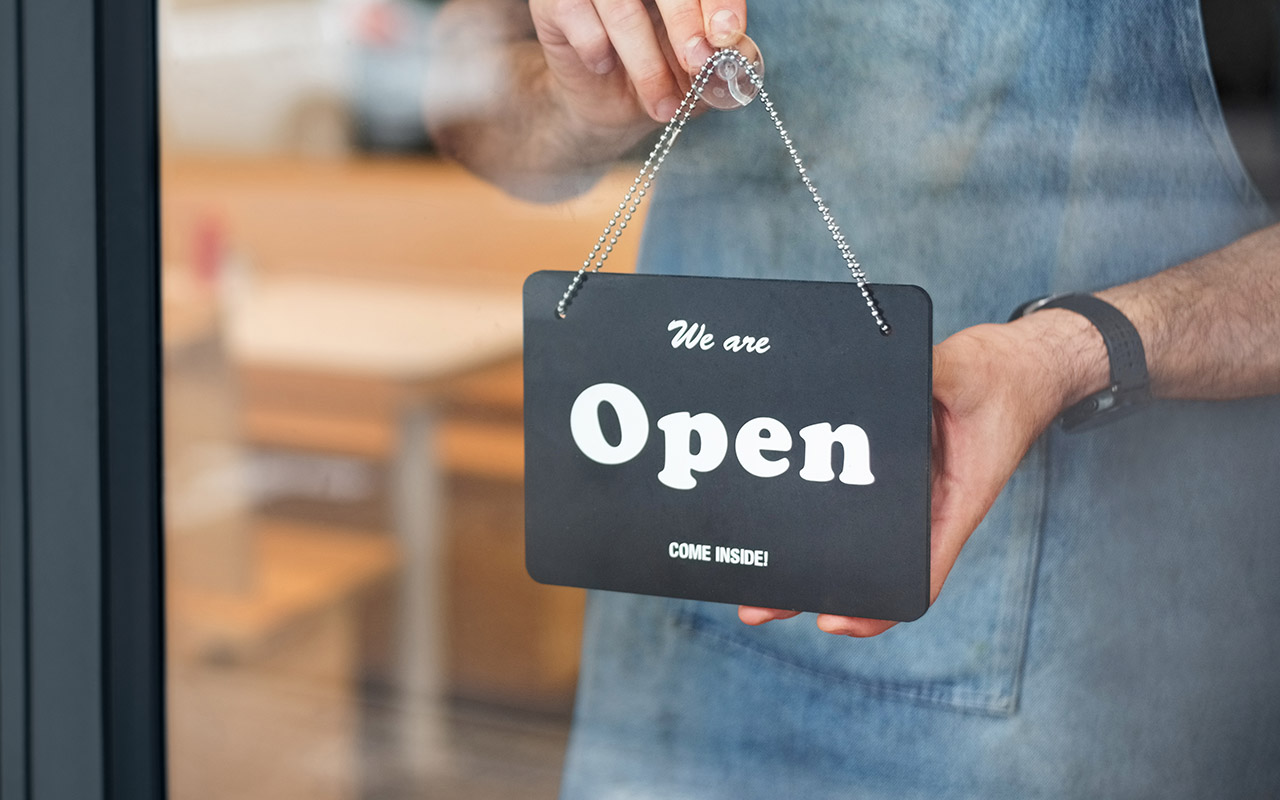 Image of a shopkeeper flipping over an open sign in the store window