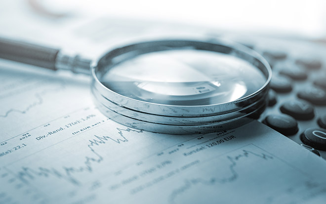 Image of a magnifying glass, calculator and charts on paper