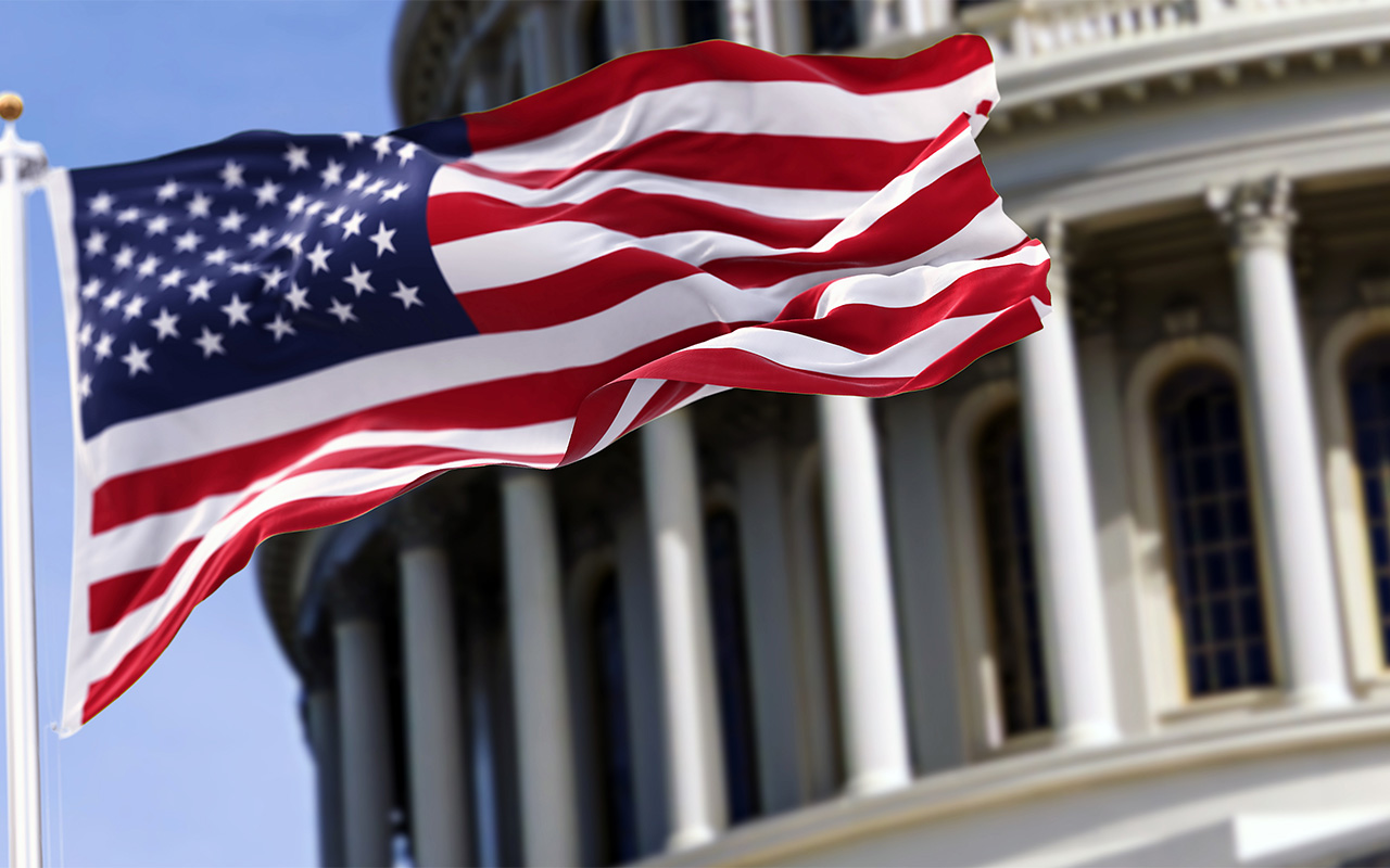 Photo of an American flag waving in front of the U.S. Capitol