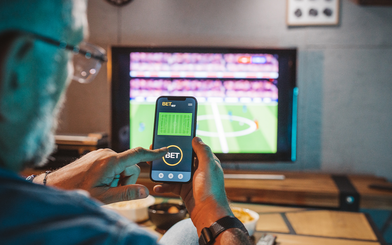 Person looking at a mobile device while watching a soccer game.