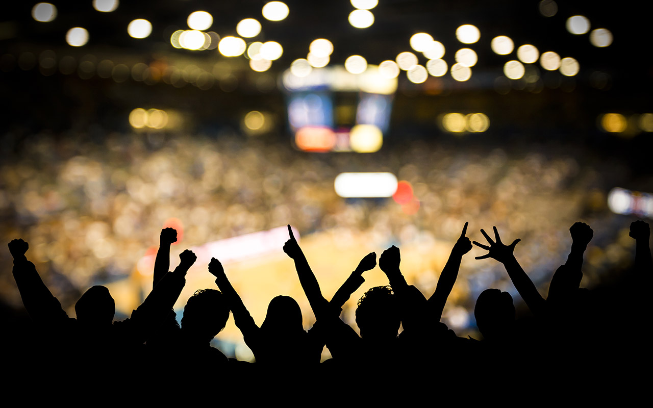 Fans excited at basketball game. Silhouetted fans raising arms in celebration at a basketball game.