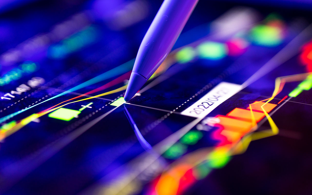 A business person tracking the technical movement of a stock chart on a computer screen