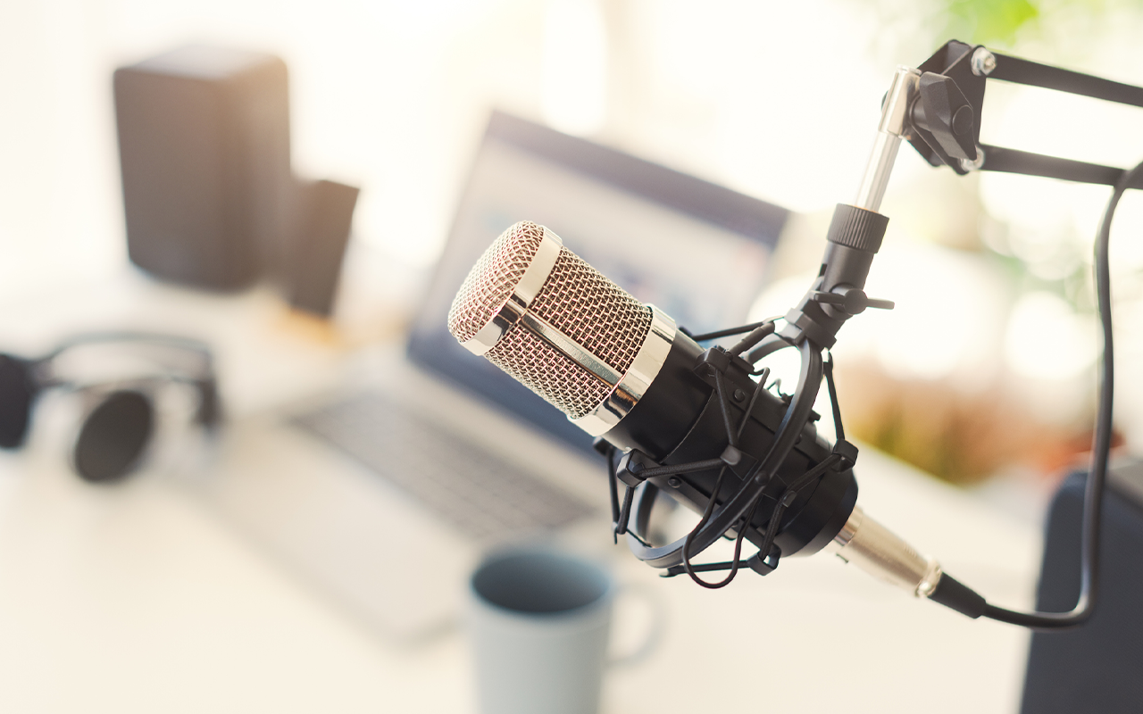 podcast microphone with a computer in the background