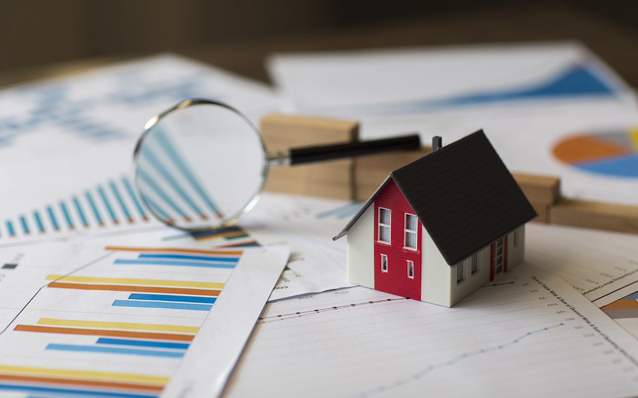 Image of toy home, magnifying glass and spreadsheets